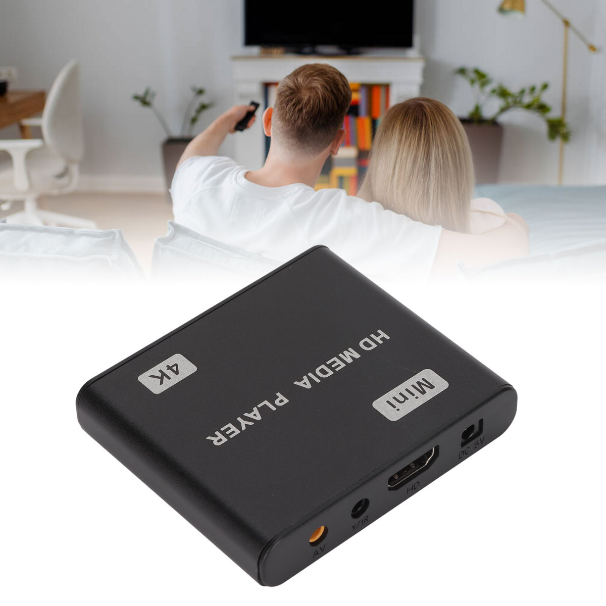 Ein schwarzer HD-Media-Player mit 4K- und Mini-Etiketten. Ein Paar schaut im Hintergrund fern.