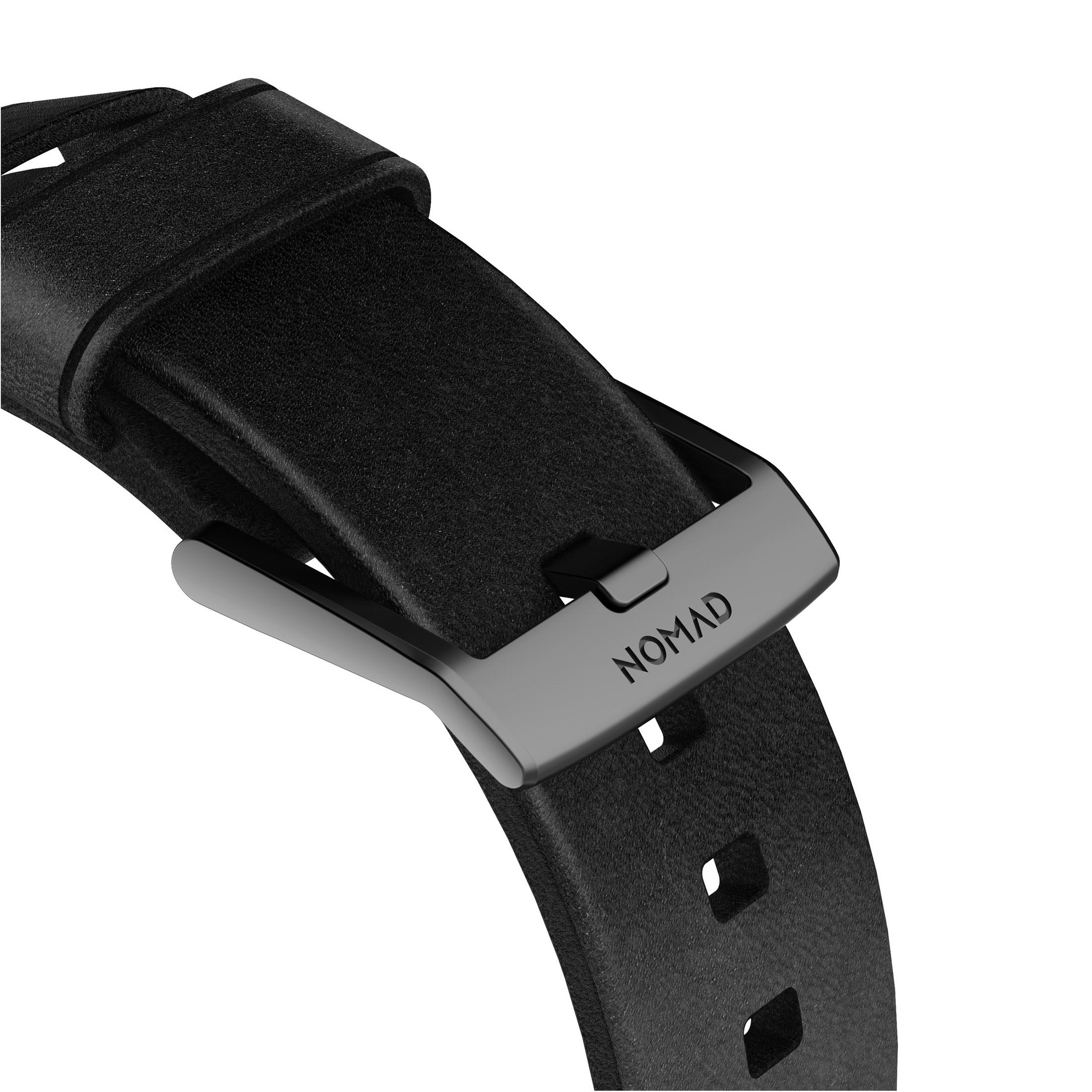 Schwarzes Nomad-Uhrenarmband, befestigt mit einer Nomad-Schließe. Das Wort 'NOMAD' ist auf der Schließe eingraviert.