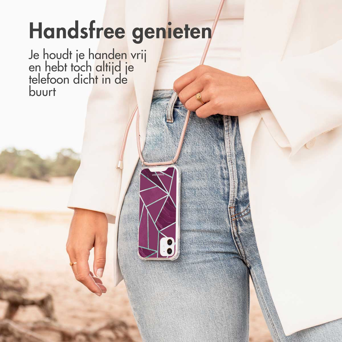 Vrouw met telefoonhoesje met riem, wandelt in de buurt van een strand. Tekst overlay.