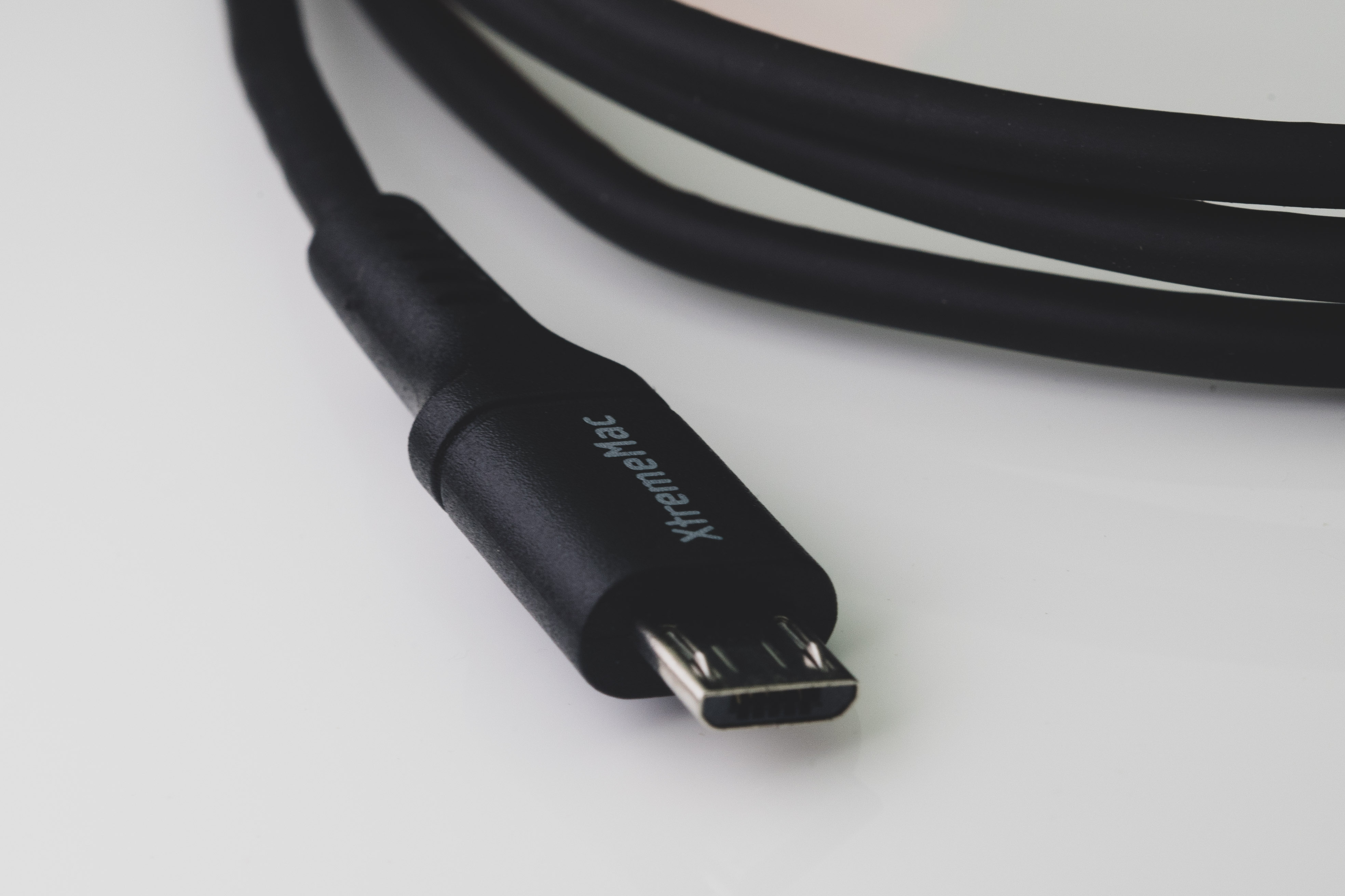 Zwarte kabel met een micro USB-connector. De achtergrond is een wit oppervlak.