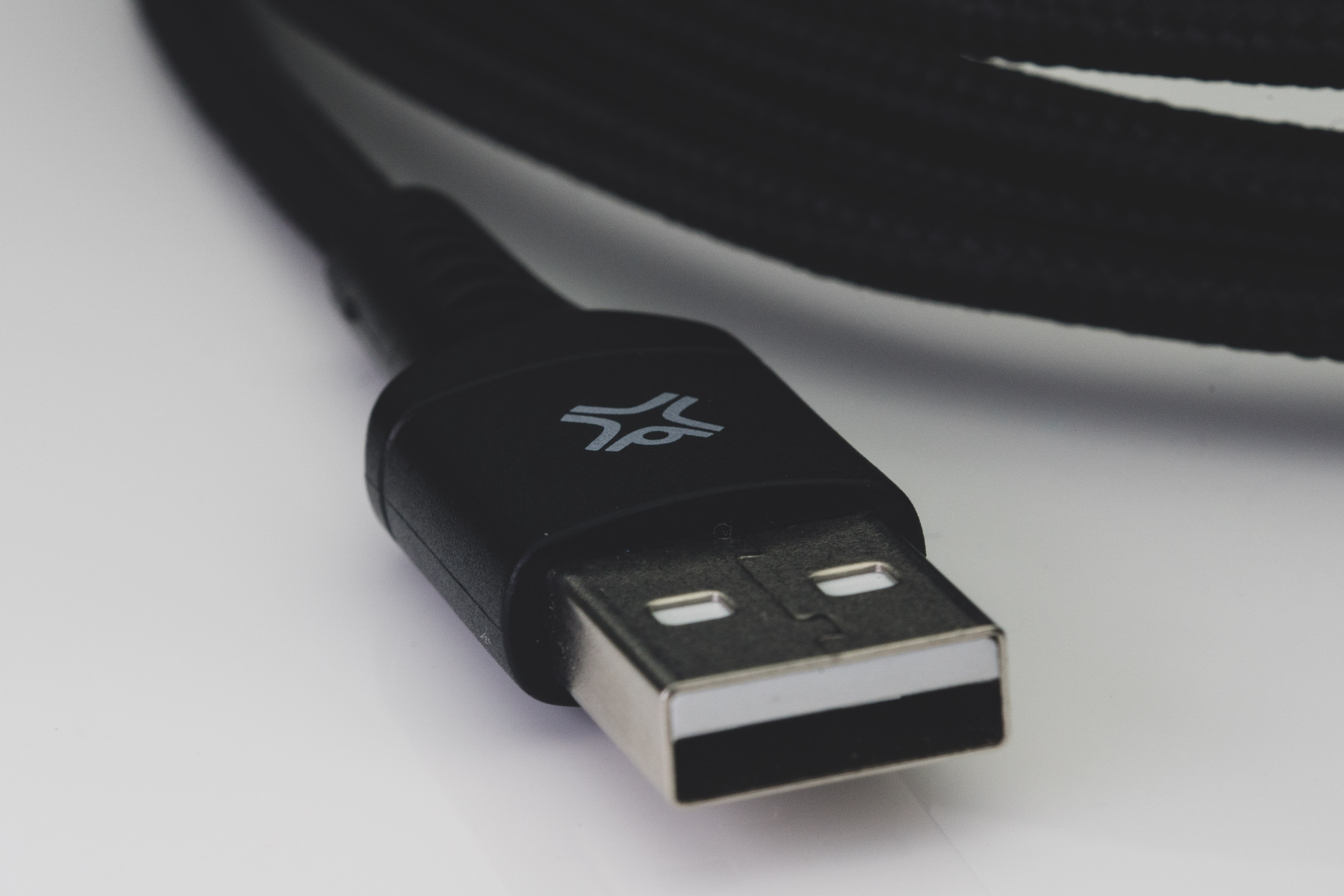 Zwarte USB-kabel met connector, witte achtergrond.