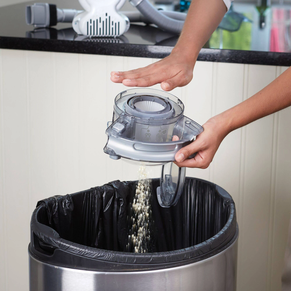 Osoba opróżnia odkurzacz do kosza na śmieci. Filtr jest usuwany.