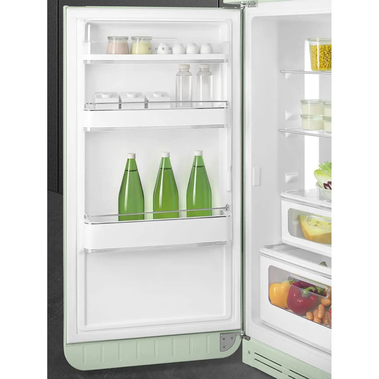 Interior de refrigerador abierto. Botellas de agua, frascos y verduras almacenados.