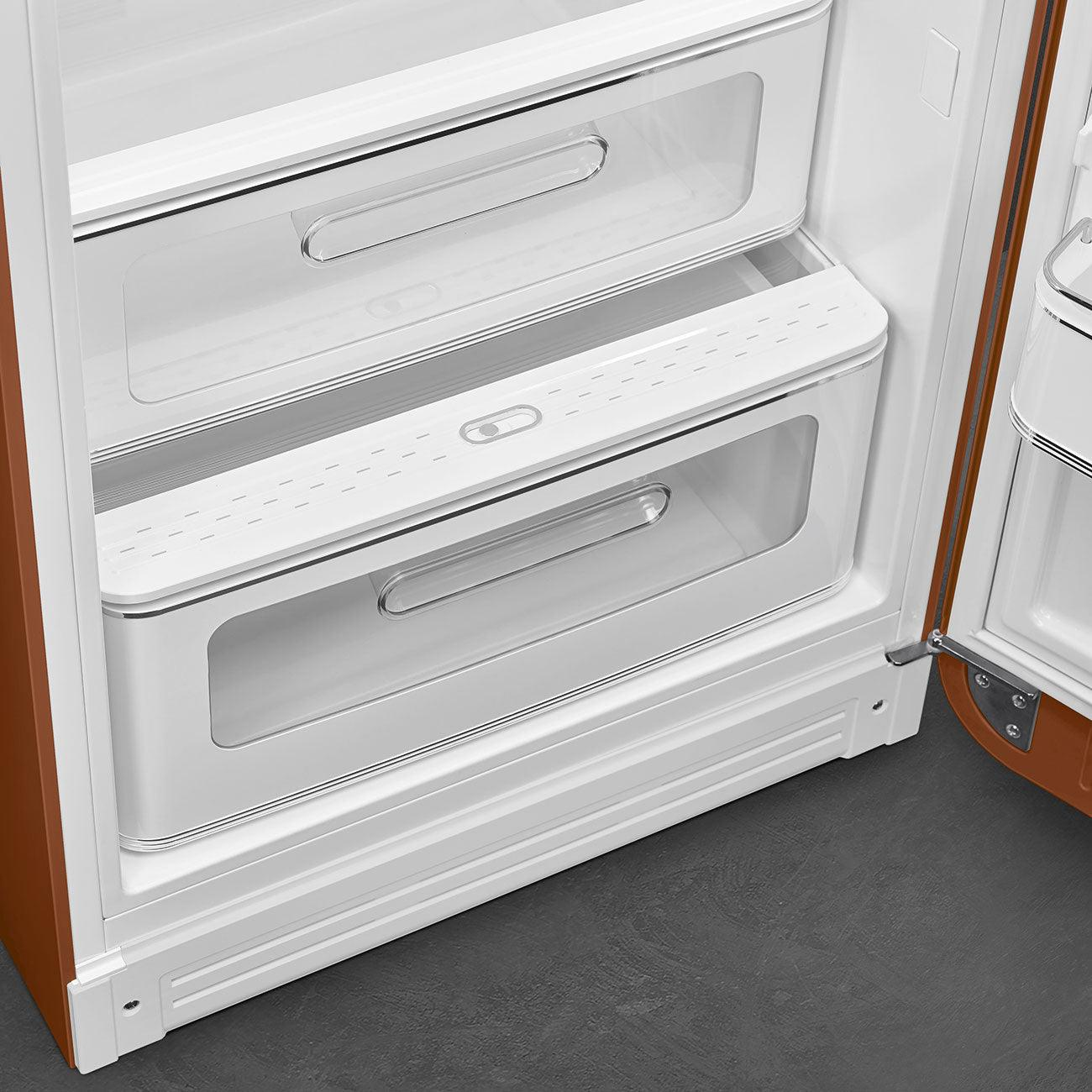 Interno del frigorifero arancione e bianco. Due cassetti, contenitori trasparenti e una maniglia.