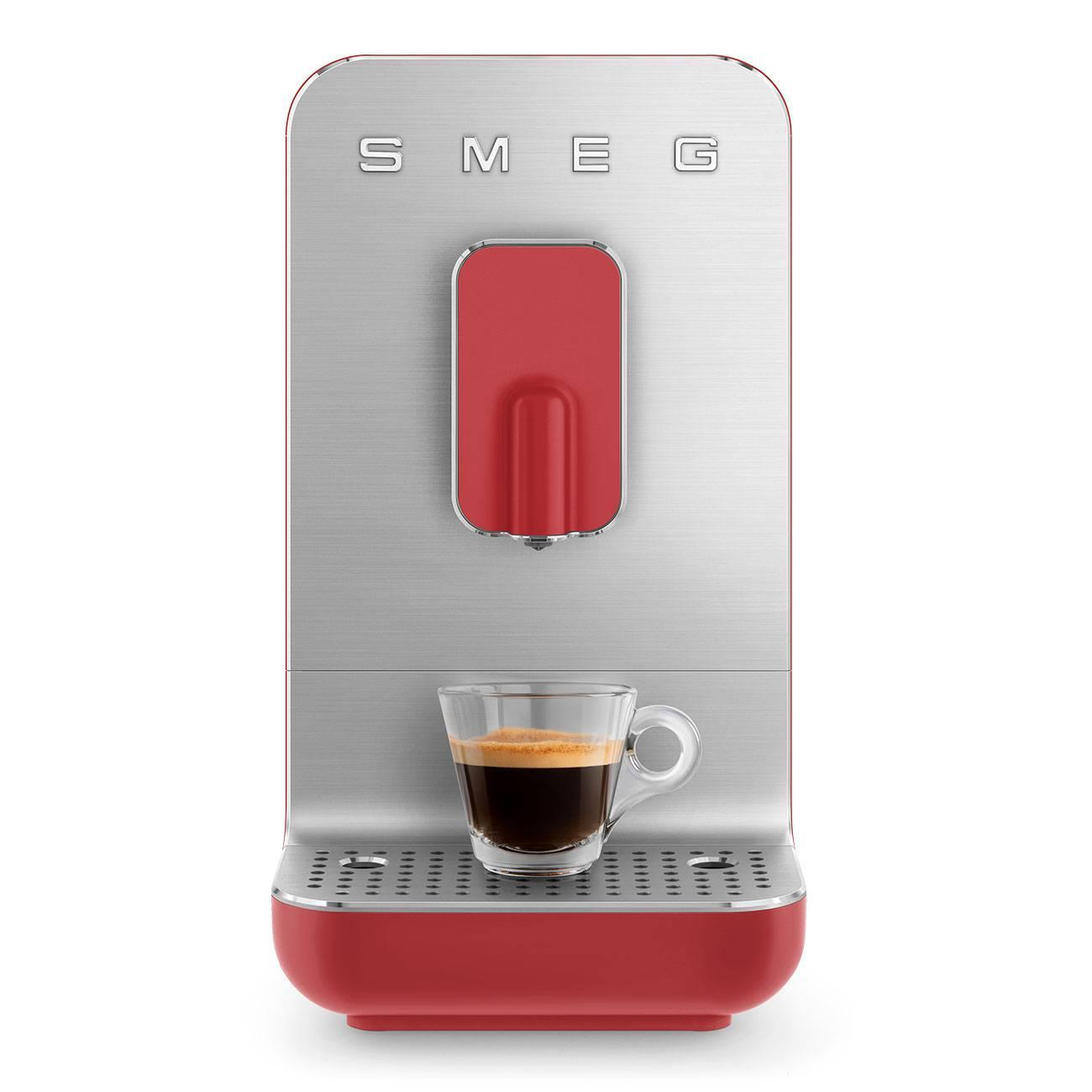 Una máquina de espresso roja y plateada con una taza de vidrio llena de café. La máquina tiene el logo SMEG.