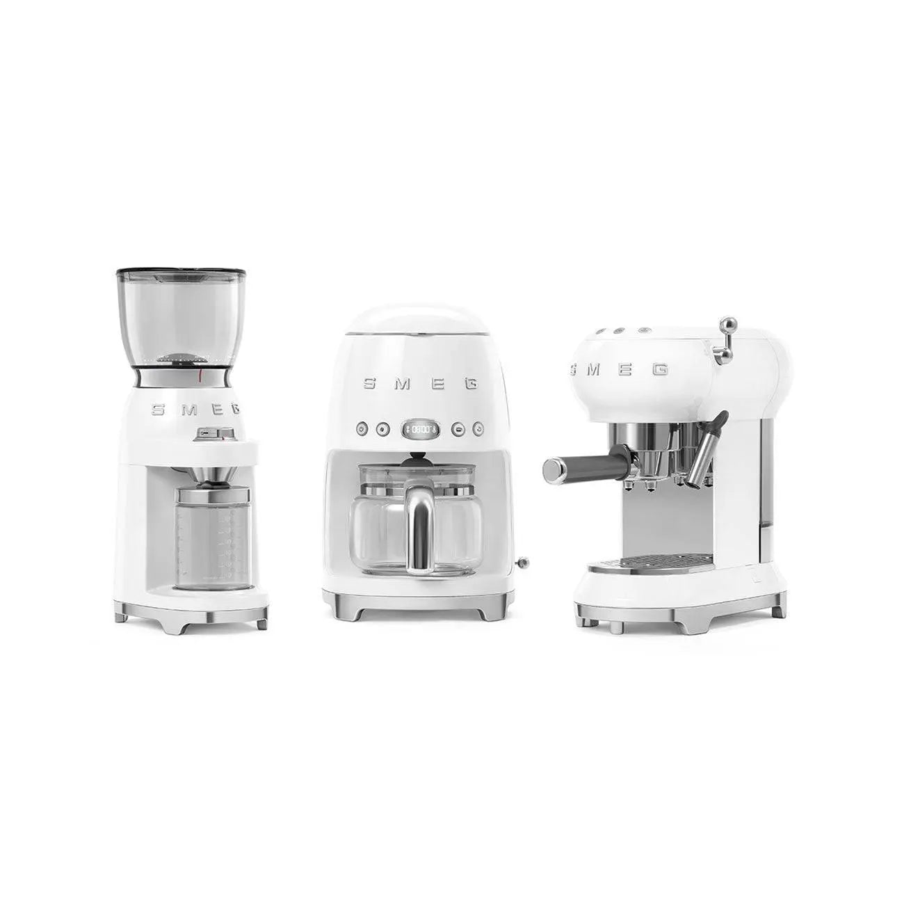Drei weiße SMEG Küchengeräte: eine Mühle, eine Kaffeemaschine und eine Espressomaschine.