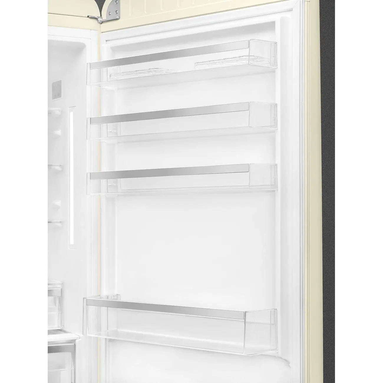 Refrigerador abierto con estantes transparentes y molduras metálicas. Vista interior, mostrando estantes vacíos dentro de una nevera crema.