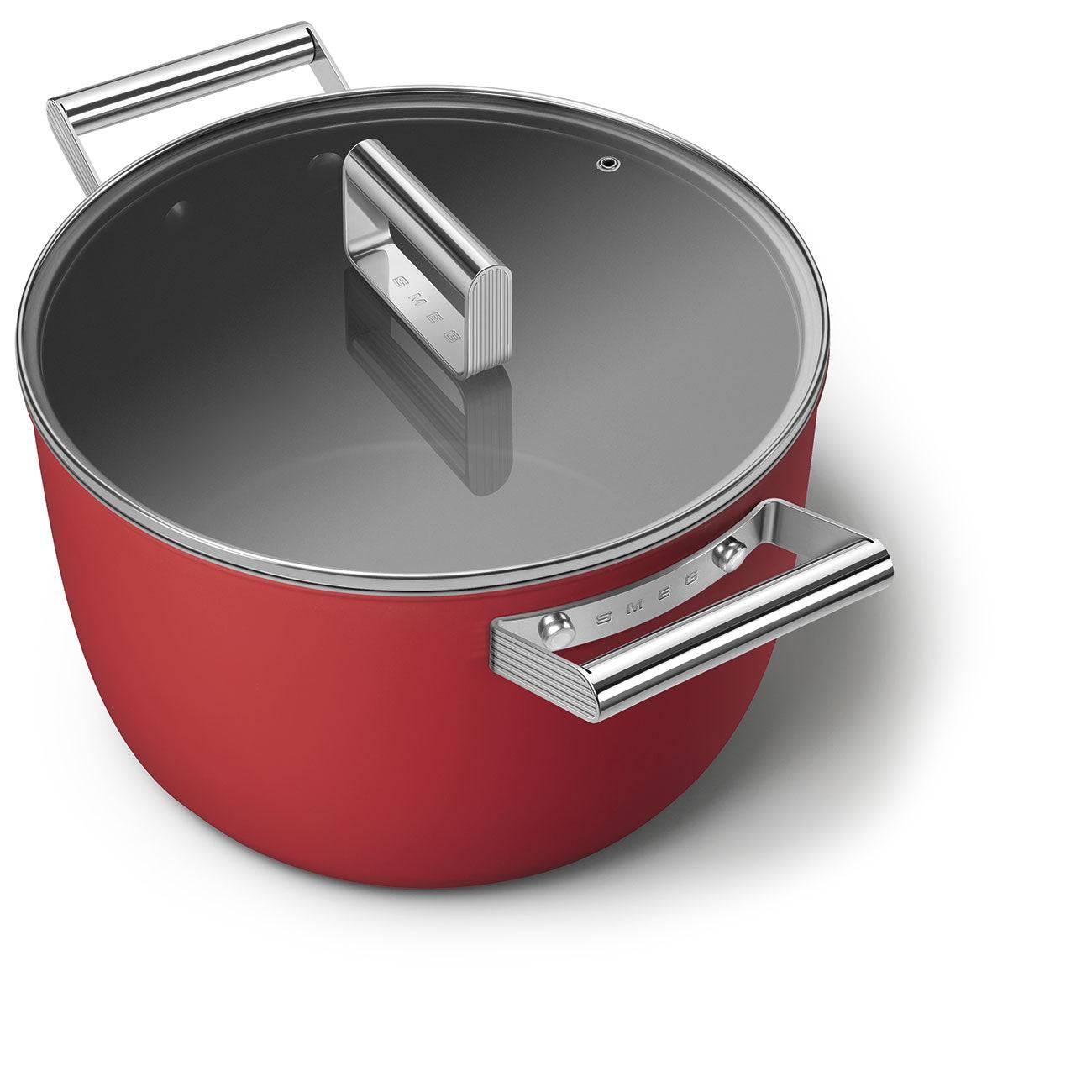Cam kapaklı ve iki gümüş kulplu kırmızı tencere. Smeg logosu mevcut.