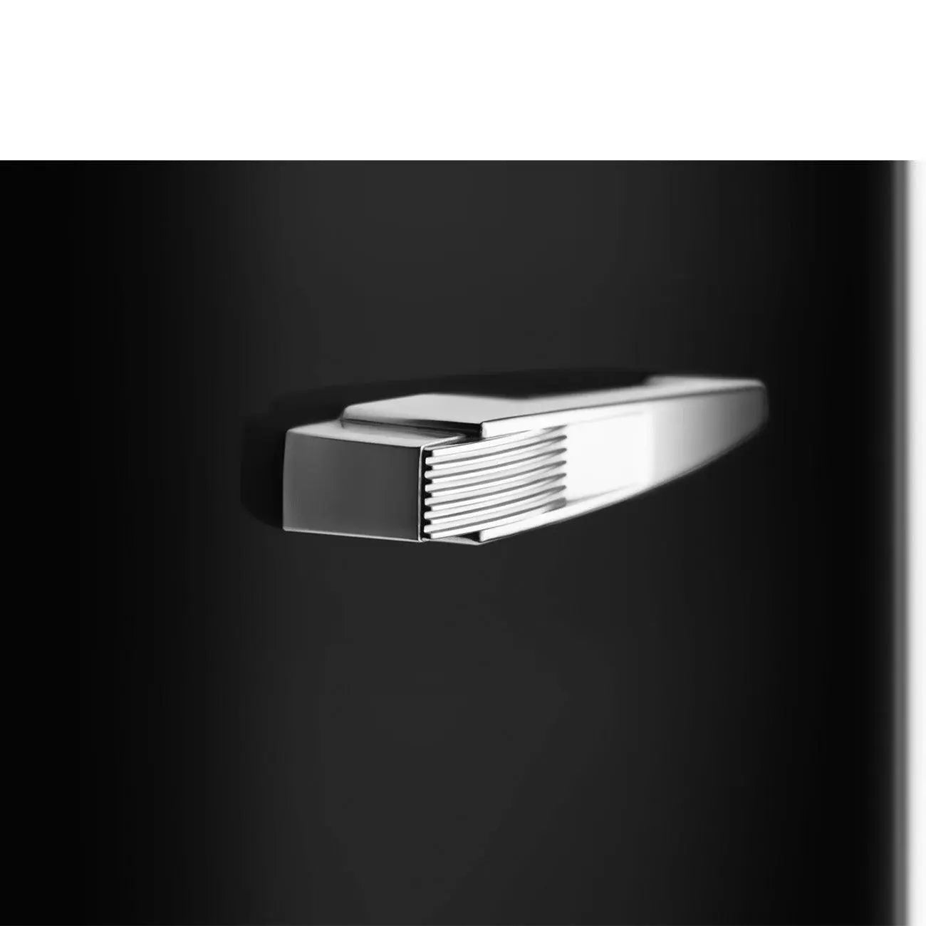 Ein schwarzer Griff auf schwarzem Untergrund. Der Griff ist silberfarben und hat horizontale Linien.