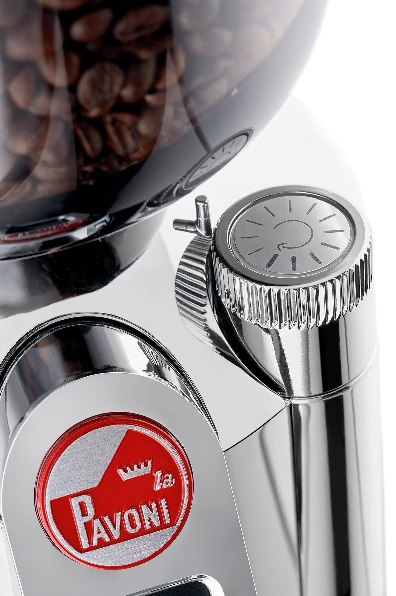 Nahaufnahme einer Espresso-Maschine aus Chrom. Die Oberseite hat ein Zifferblatt. Ein Kaffeebohnenbehälter ist sichtbar. Rotes La Pavoni-Logo vorne.