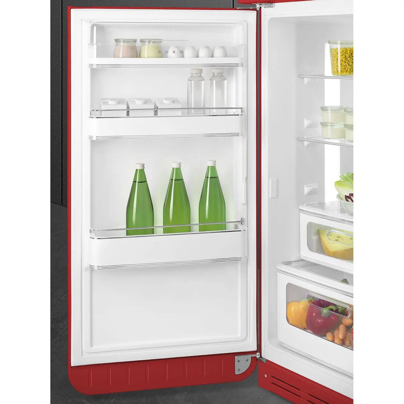 Interior de un refrigerador Smeg rojo. Está lleno de comida y bebidas. Botellas verdes en el medio.