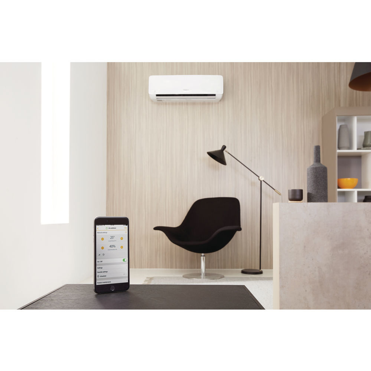 Interno di una stanza con condizionatore a parete. Un telefono con un'app è sul tavolo.