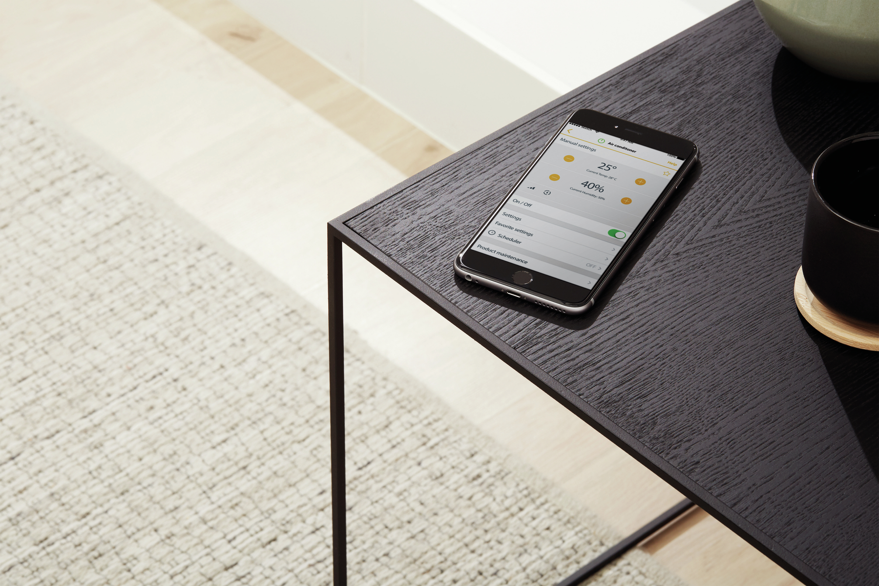 Un tavolo nero con uno smartphone che mostra un'app di temperatura e programmazione.