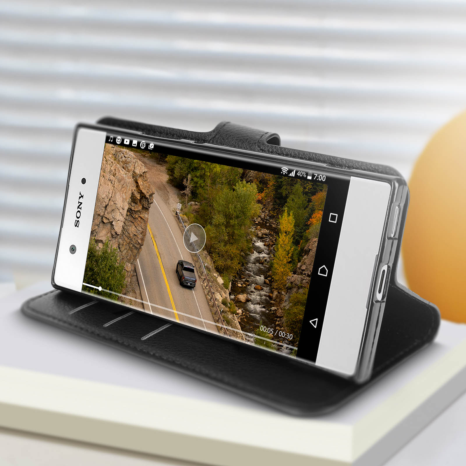 Un telefono in una custodia riproduce un video di una strada. La custodia è in una custodia nera.