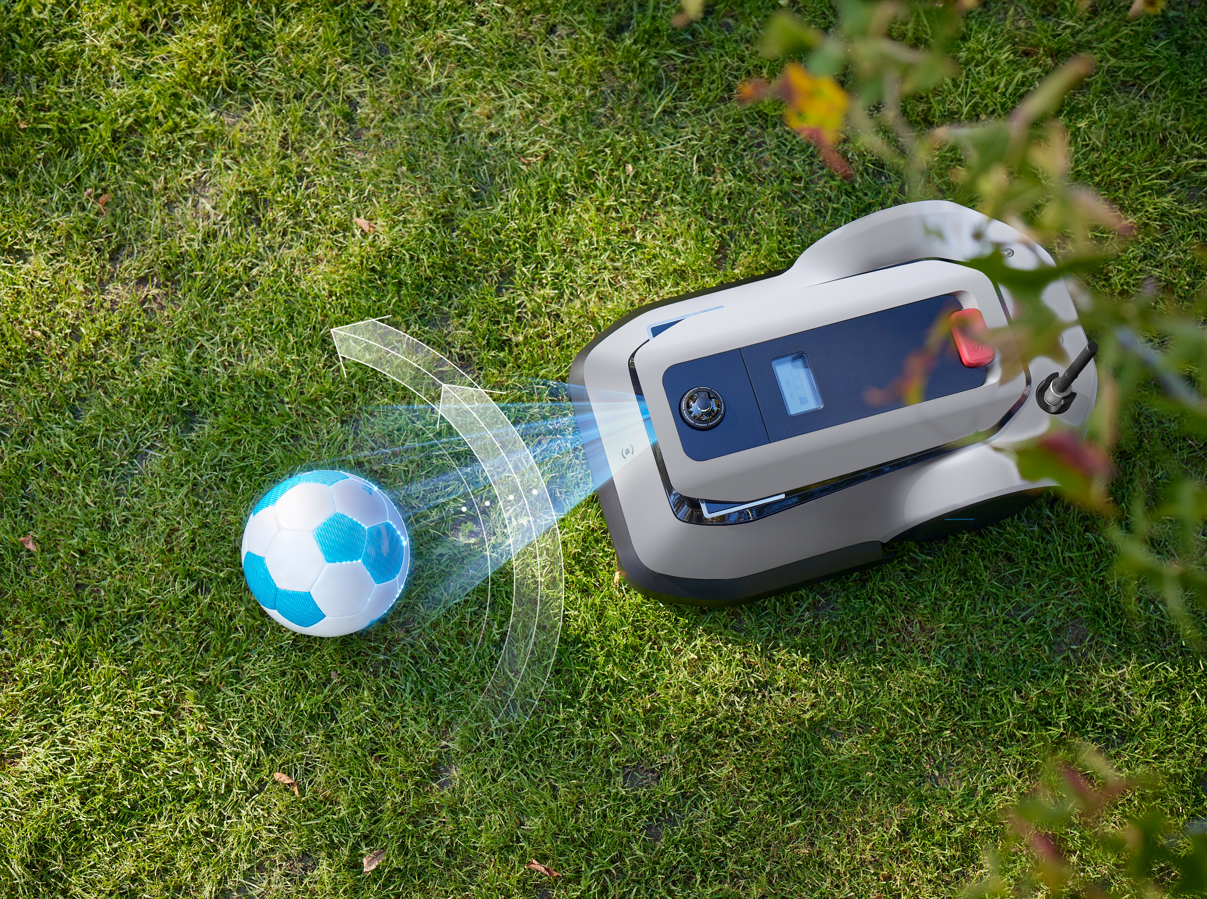 Ein Roboter-Rasenmäher auf Gras, in der Nähe eines Fußballs und Pflanzen.