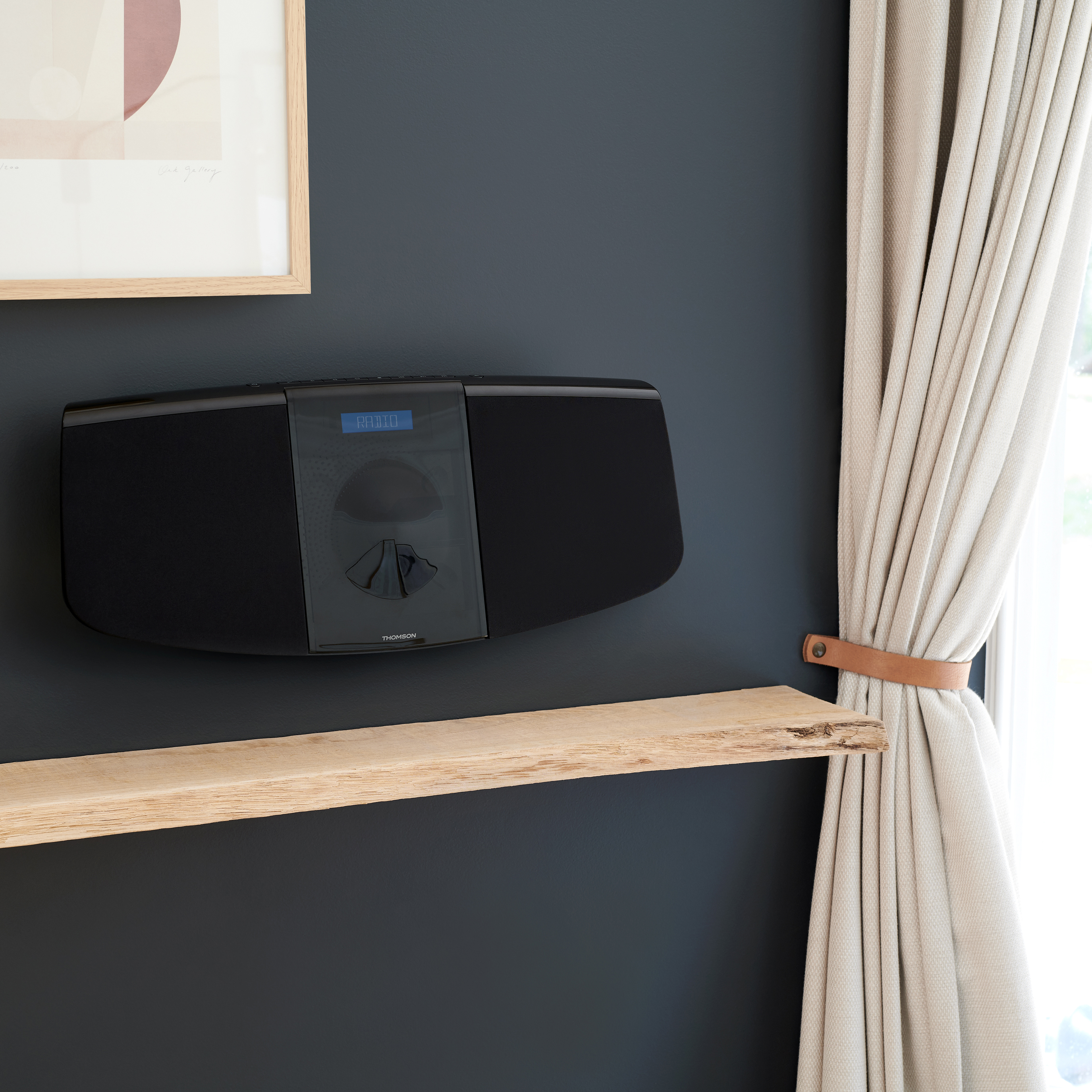 Czarny system dźwiękowy na ciemnej ścianie, z drewnianą półką i zasłonami.