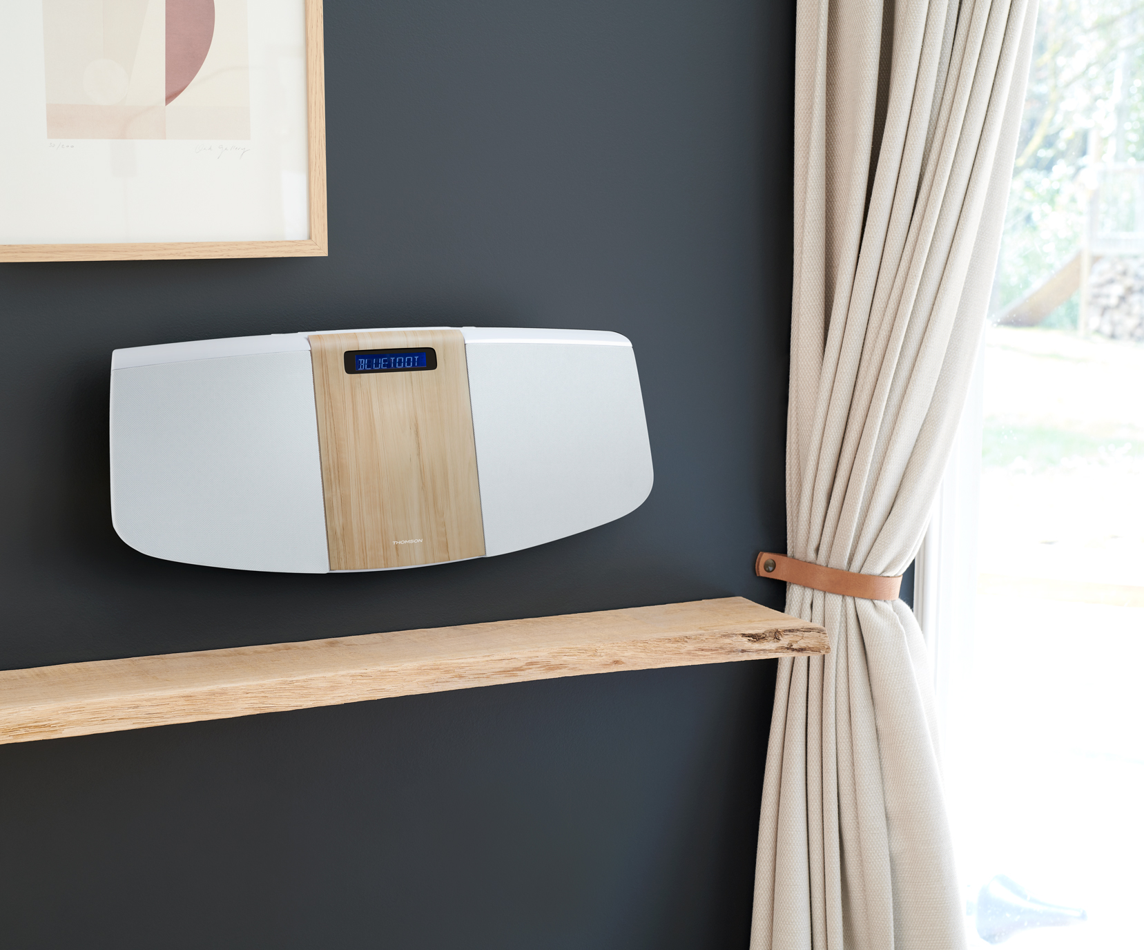 Biały i drewniany głośnik na ciemnoszarej ścianie z drewnianą półką i zasłoną.