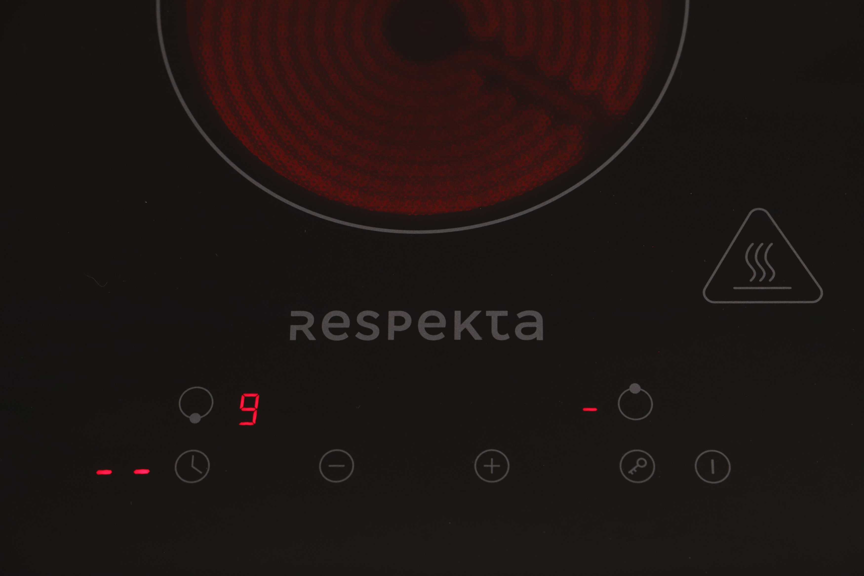 A black stove top with red lit numbers and a heating element, with the word Respekta.