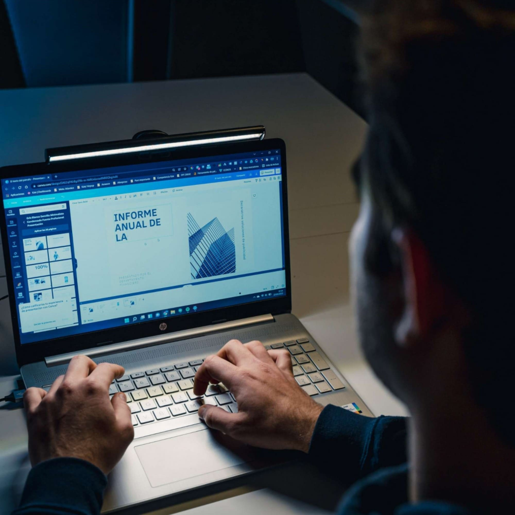 Persona escribiendo en una laptop, pantalla muestra un documento con gráfico de edificio.