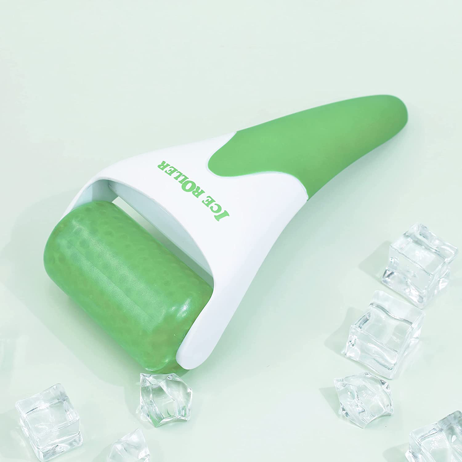 Grüner und weißer Eisroller mit Eiswürfeln auf mintgrüner Oberfläche.