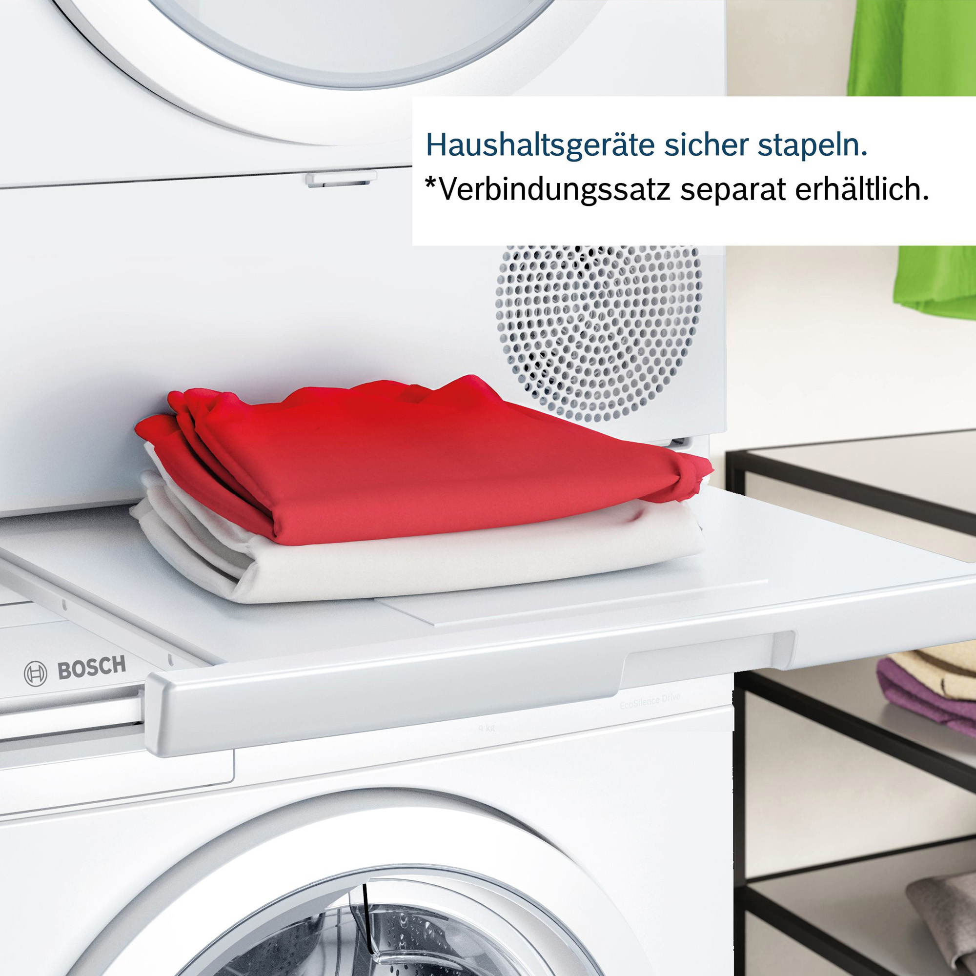 Ein Waschmaschinen- und Trockner-Setup. Der Trockner hat gefaltete rote und weiße Kleidung auf einem Regal.