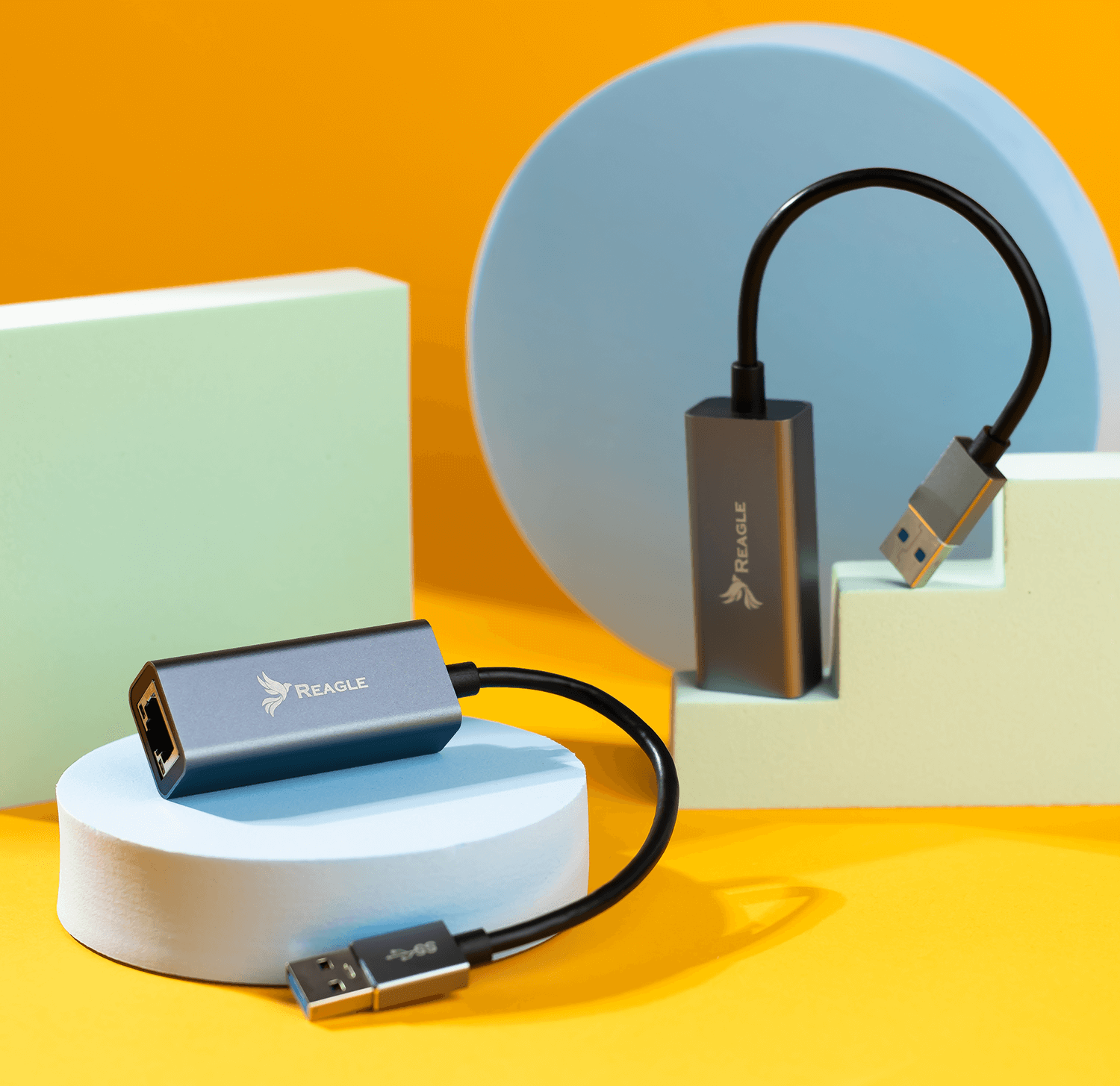 Kable adaptera sieciowego. Kolory niebieski i szary. Podłączone na niebieskiej i białej powierzchni. Żółte tło.