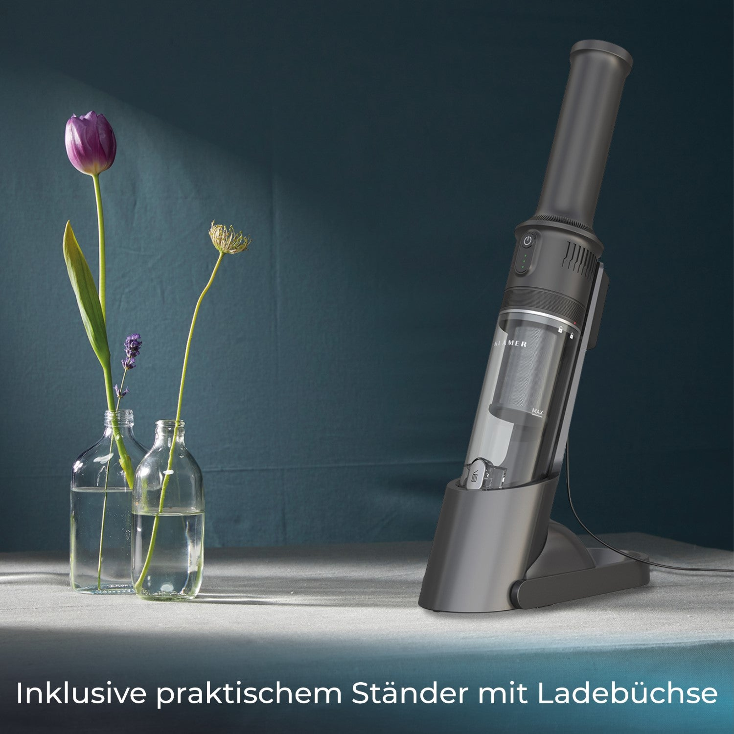 Handstaubsauger mit Ladestation, Blumen in Vasen auf einem Tisch.