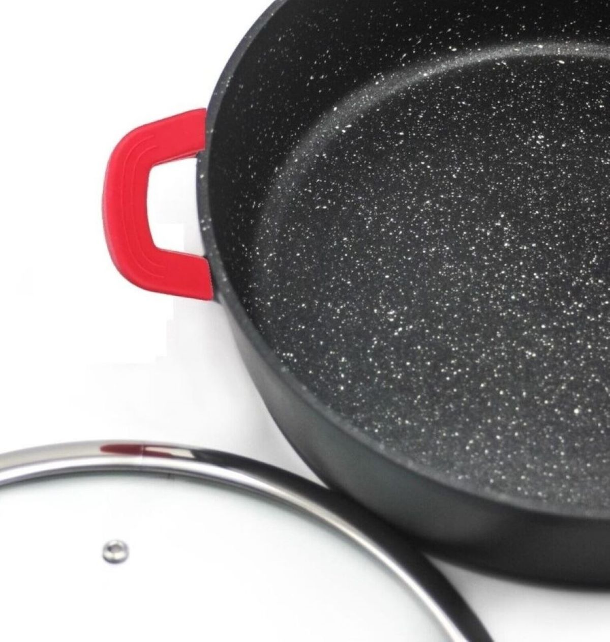 Schwarze Pfanne mit rotem Griff und Glasdeckel. Die Pfanne hat weiße Sprenkel.
