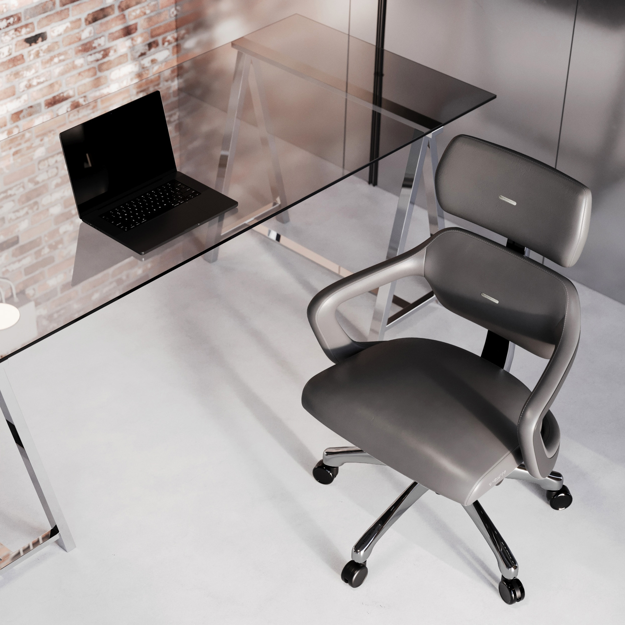Ein modernes Büro mit Glastisch, schwarzem Laptop, grauem Stuhl und Backsteinmauer.