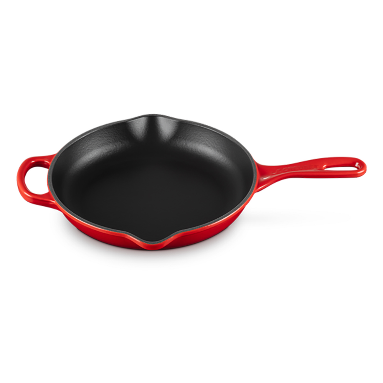 Czerwona żeliwna patelnia z długim uchwytem. Na białym tle.