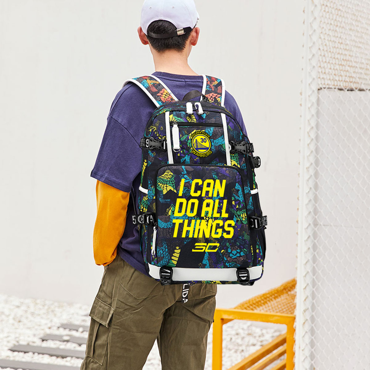 Person mit Rucksack mit den Worten 'I can do all things'. Weißer Zaun im Hintergrund.