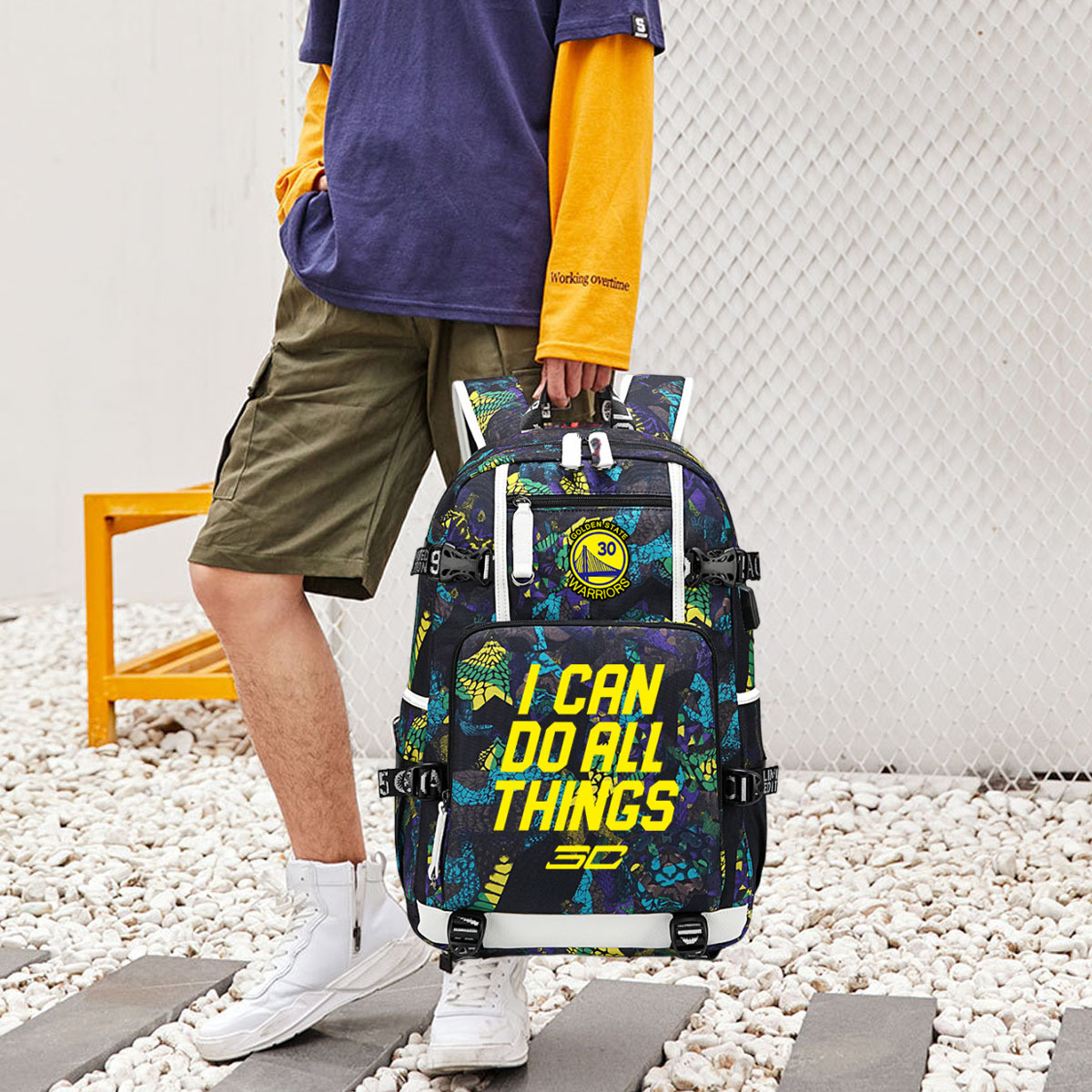 Eine Person trägt einen Rucksack mit den Worten 'I CAN DO ALL THINGS' in einer Straßenszene.