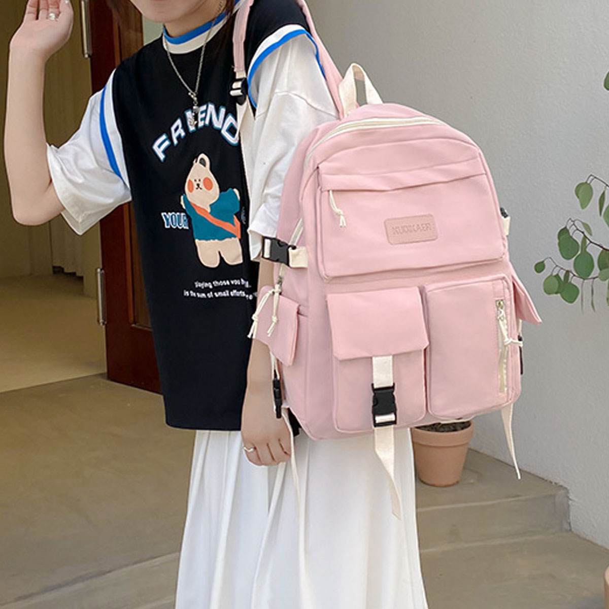 Eine Frau mit einem Rucksack. Der Rucksack ist rosa, mit mehreren Taschen und einem weißen Riemen.