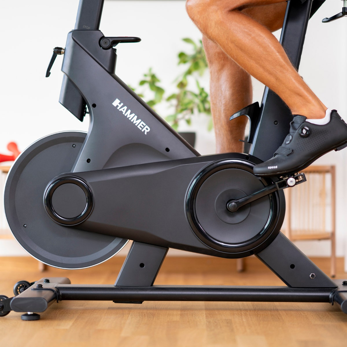 Jambes d'homme, pieds avec chaussures de cyclisme noires sur un vélo d'exercice.