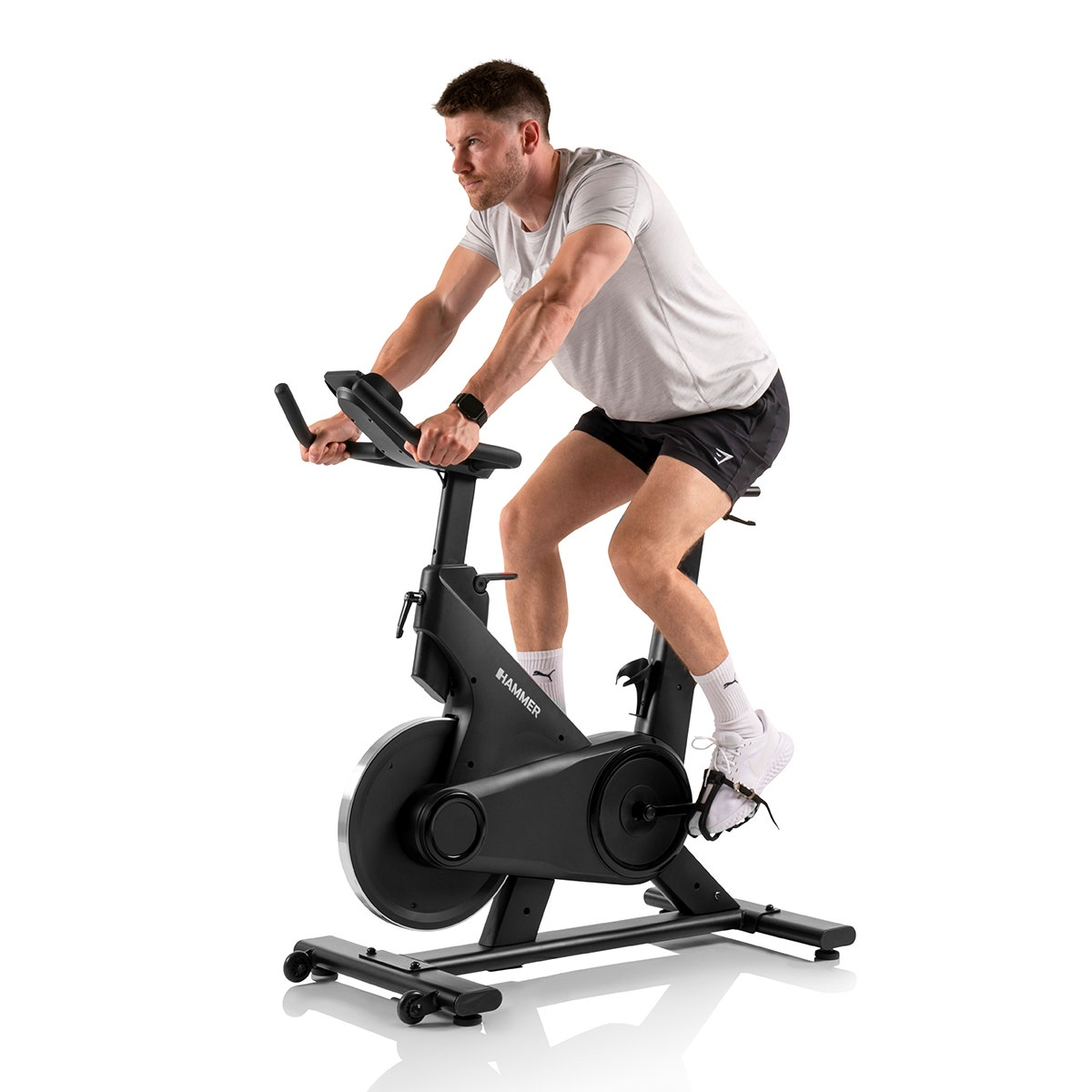 Homme en tenue de sport utilisant un vélo d'exercice stationnaire. Fond blanc.