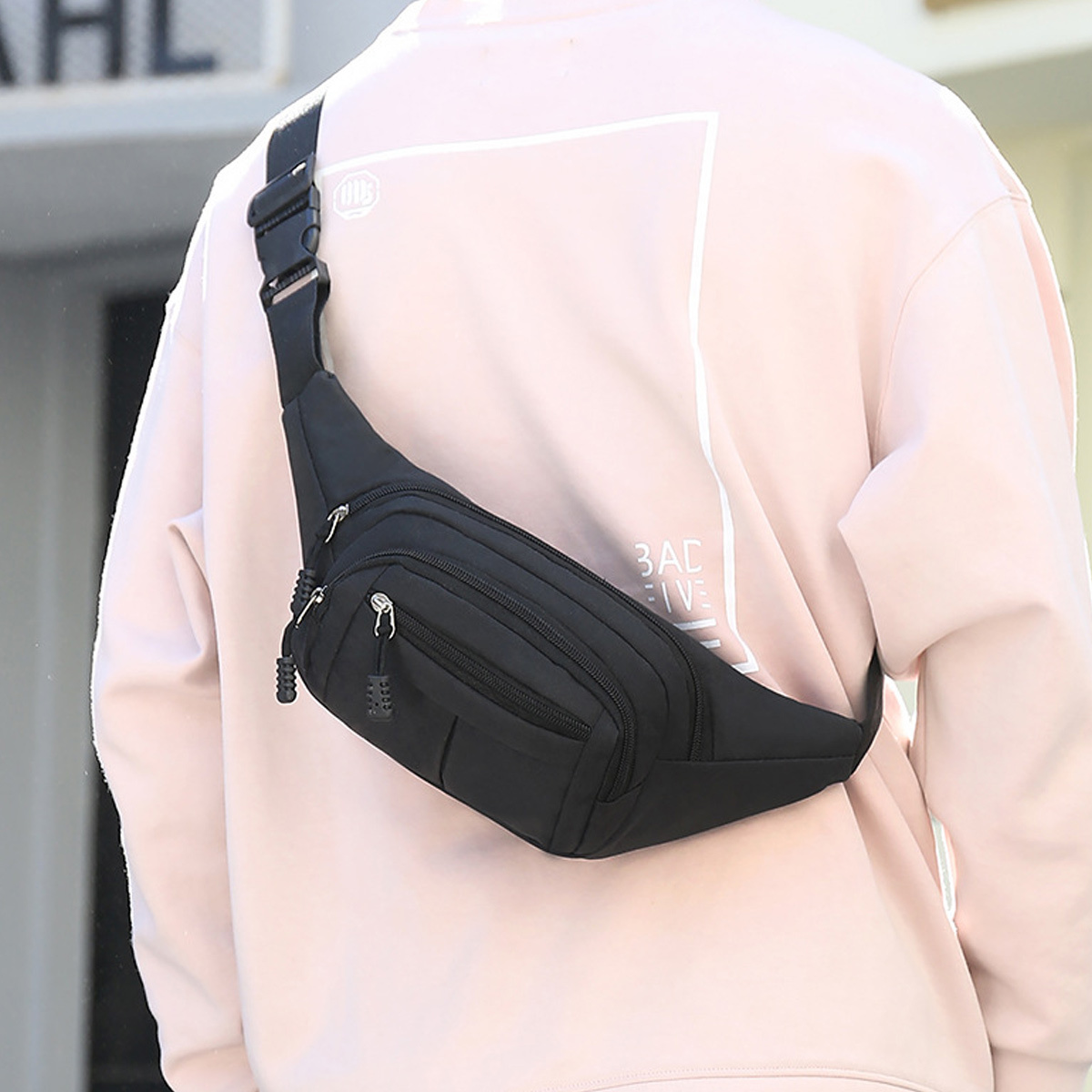 Eine Person mit einem rosa Hemd und einer schwarzen Gürteltasche um die Taille.