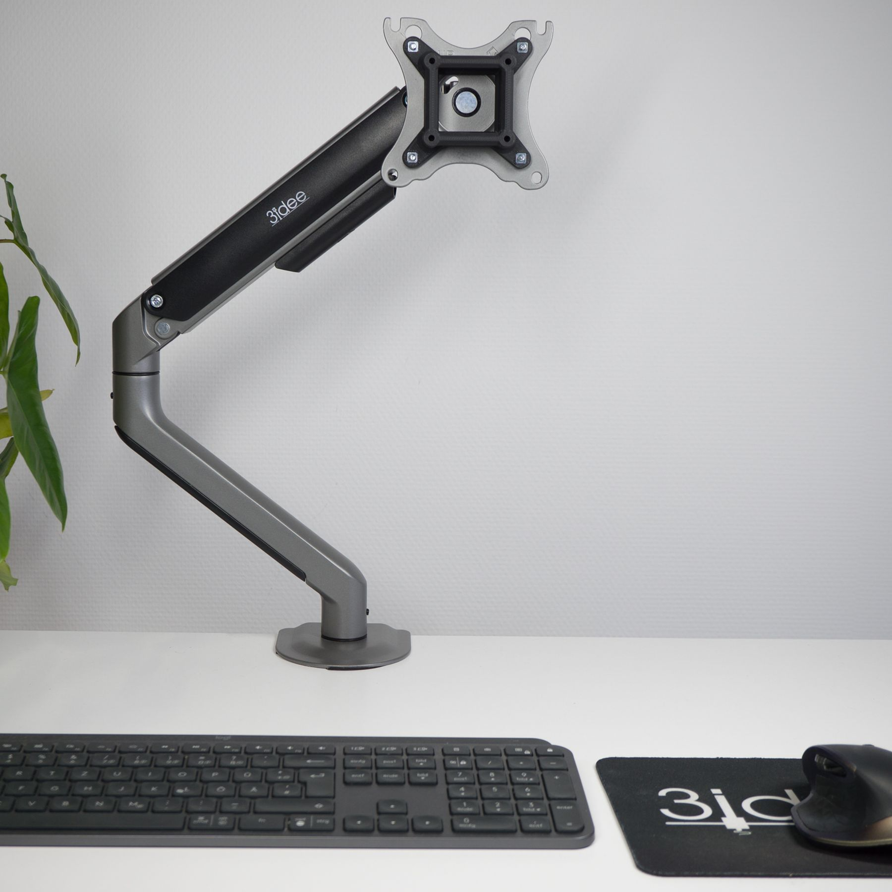 Ein Monitorarm an einem Schreibtisch befestigt. Eine Tastatur und Maus befinden sich auf dem Schreibtisch.