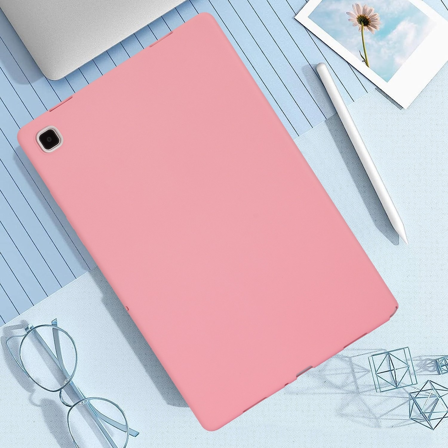 Ein rosa Tablet, ein Stift und andere Objekte auf einer blauen Oberfläche.