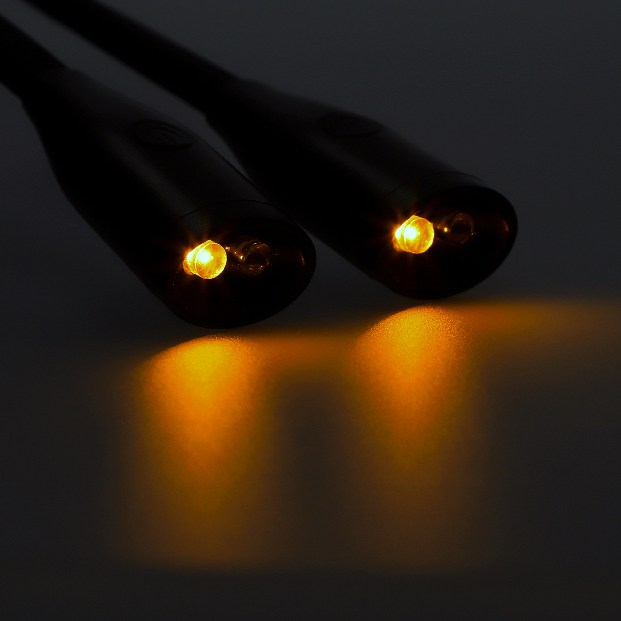 Dos luces LED brillantes con iluminación naranja en un entorno oscuro.