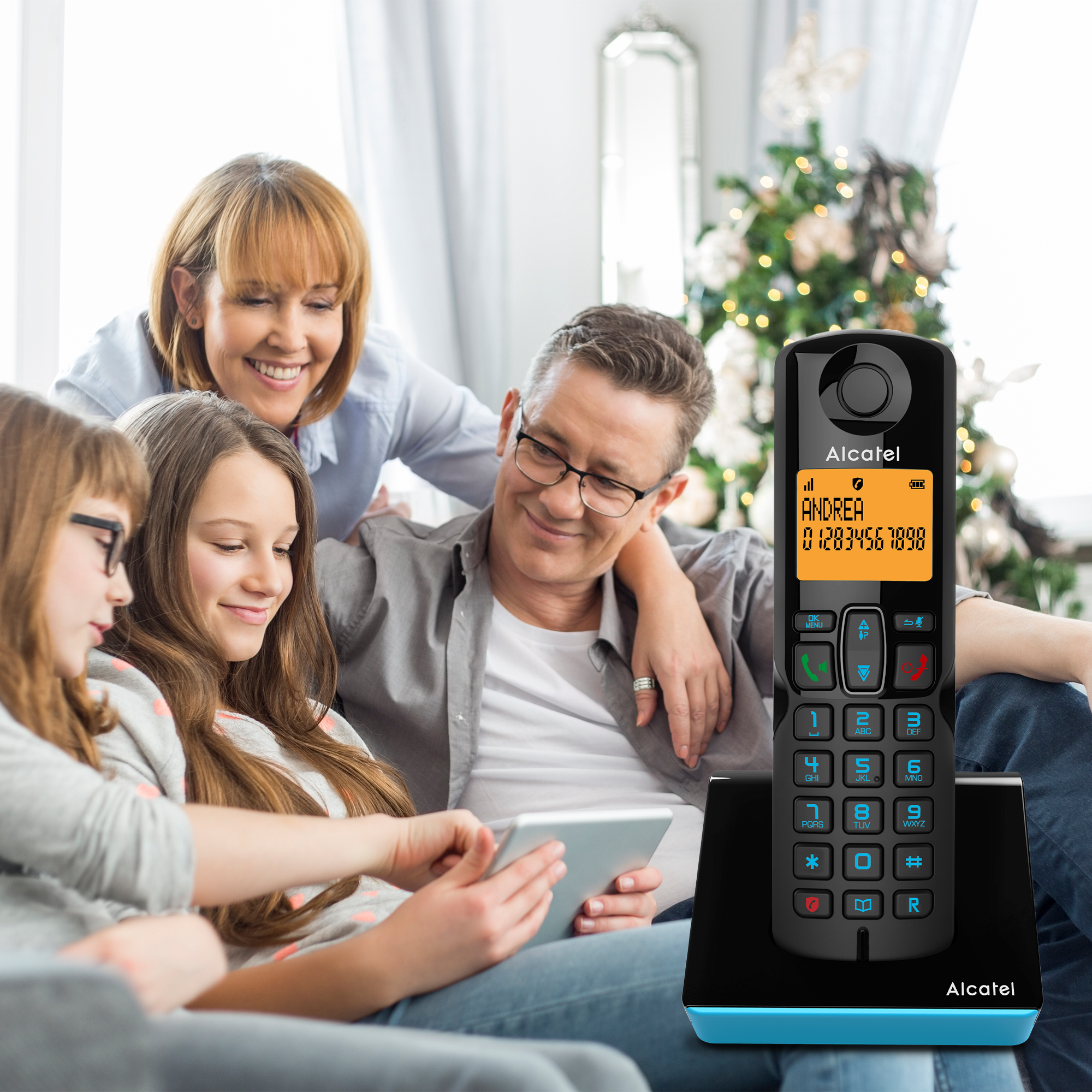 Family in a living room. A woman uses a tablet while others watch. Alcatel phone on the right.
