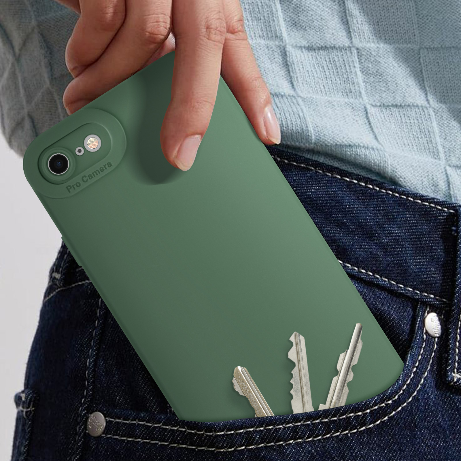 Una mano in un maglione blu tiene una custodia verde per telefono con un telefono. Le chiavi sono nella tasca dei jeans.