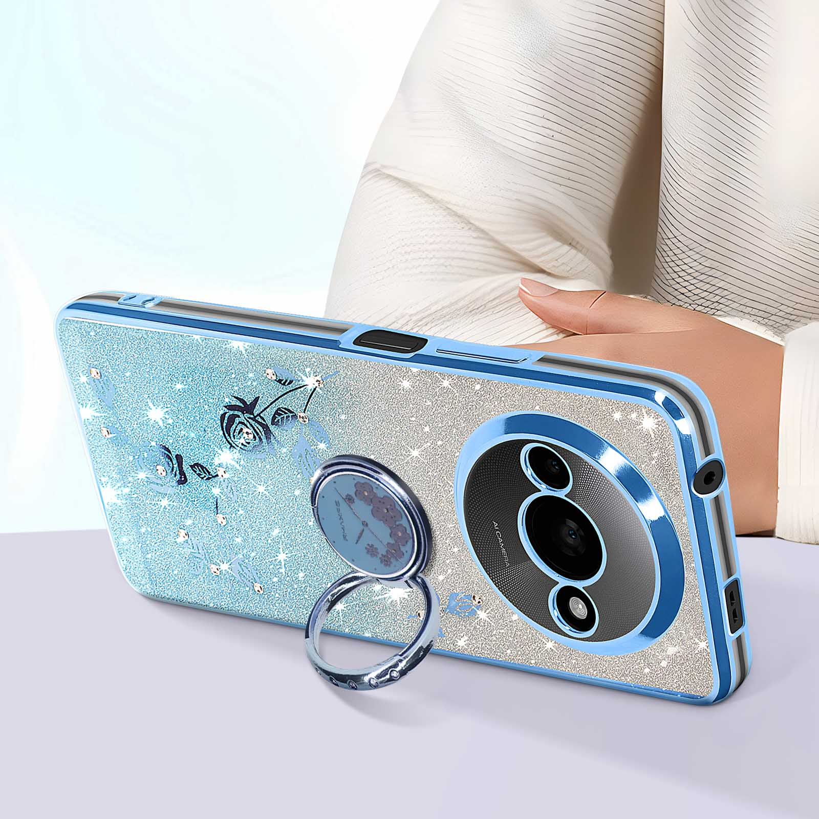 Custodia blu per telefono con design floreale. Supporto ad anello argentato. Il telefono è su una superficie.