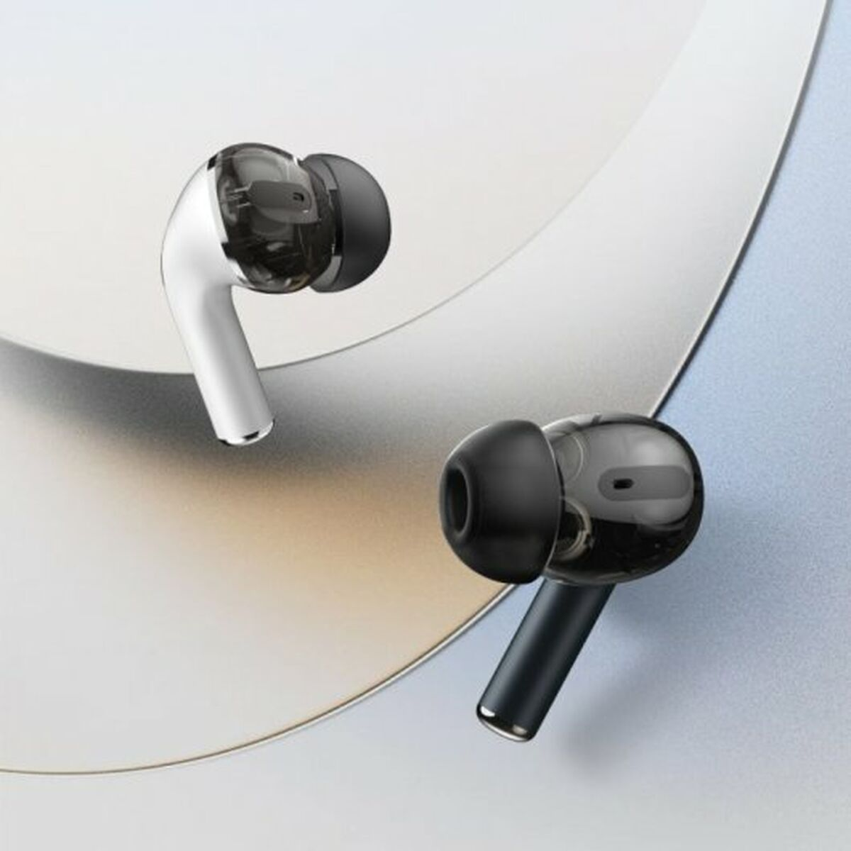 Due auricolari wireless, uno bianco, uno nero, con punte trasparenti, angolati su una superficie.