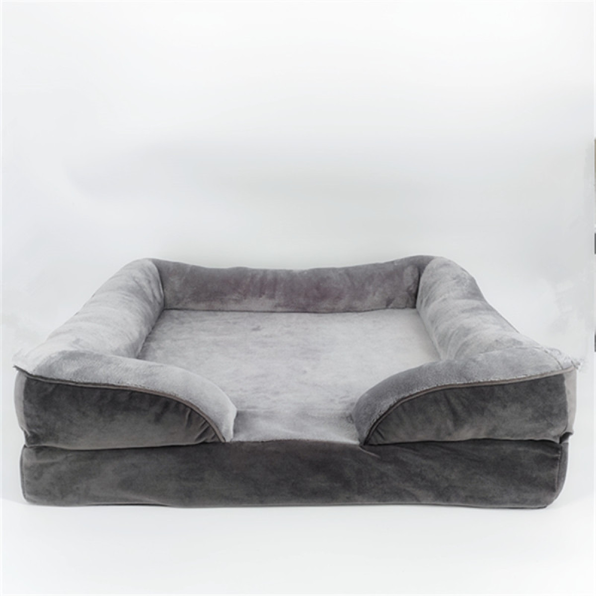 Ein graues Hundebett mit erhöhten Seiten und einer weichen, plüschigen Oberfläche auf weißem Hintergrund.