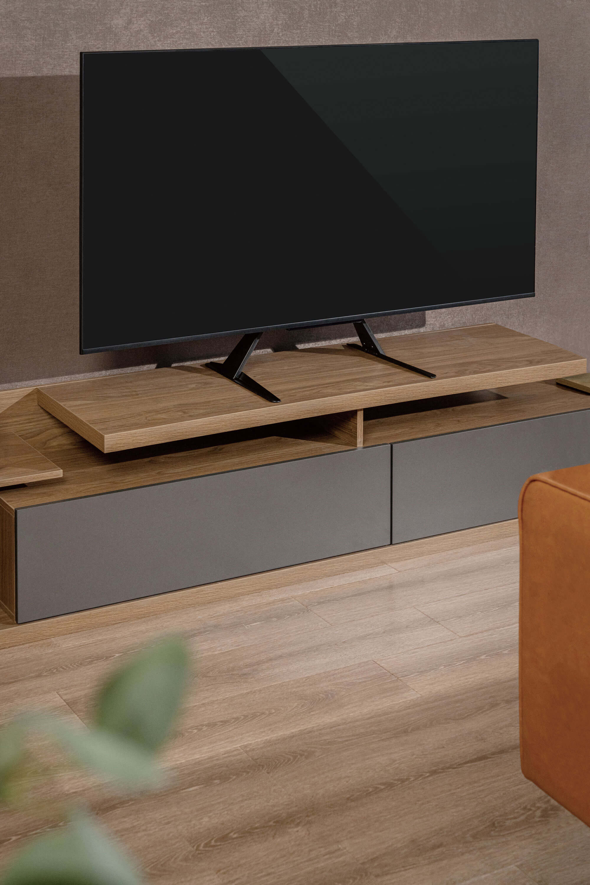 Ein modernes Wohnzimmer mit einem Fernseher auf einem Holzregal.