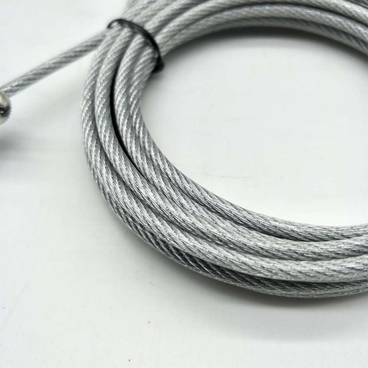 Nahaufnahme eines aufgerollten silbernen Kabels. Das Kabel liegt auf weißem Untergrund.