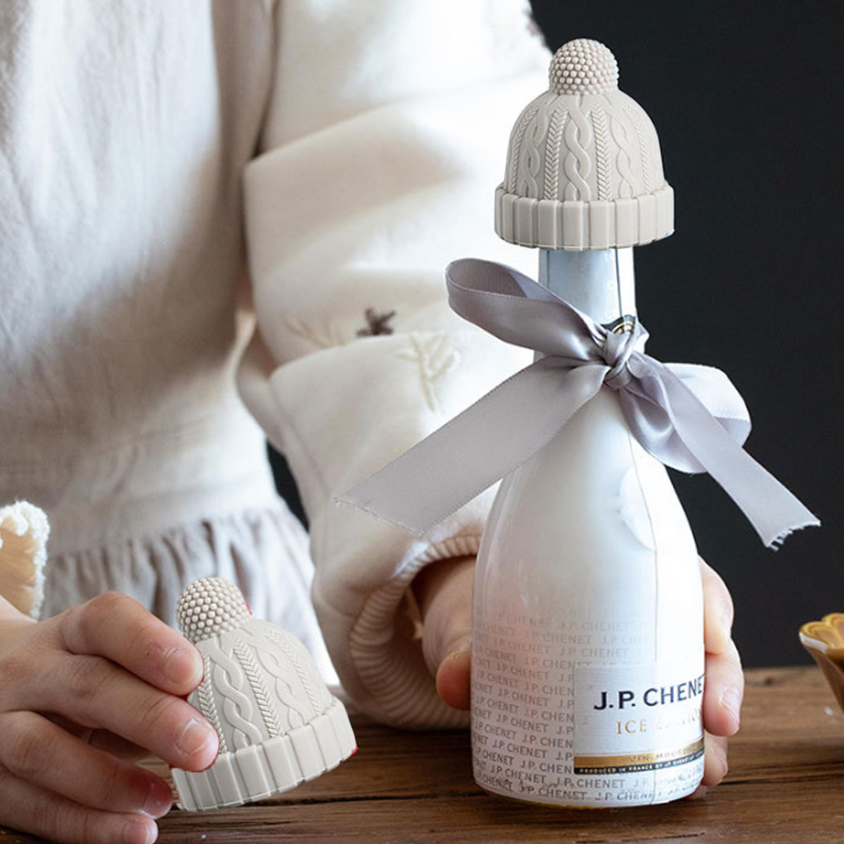 Champagnerflasche mit Strickmütze-Stöpsel und Schleife.