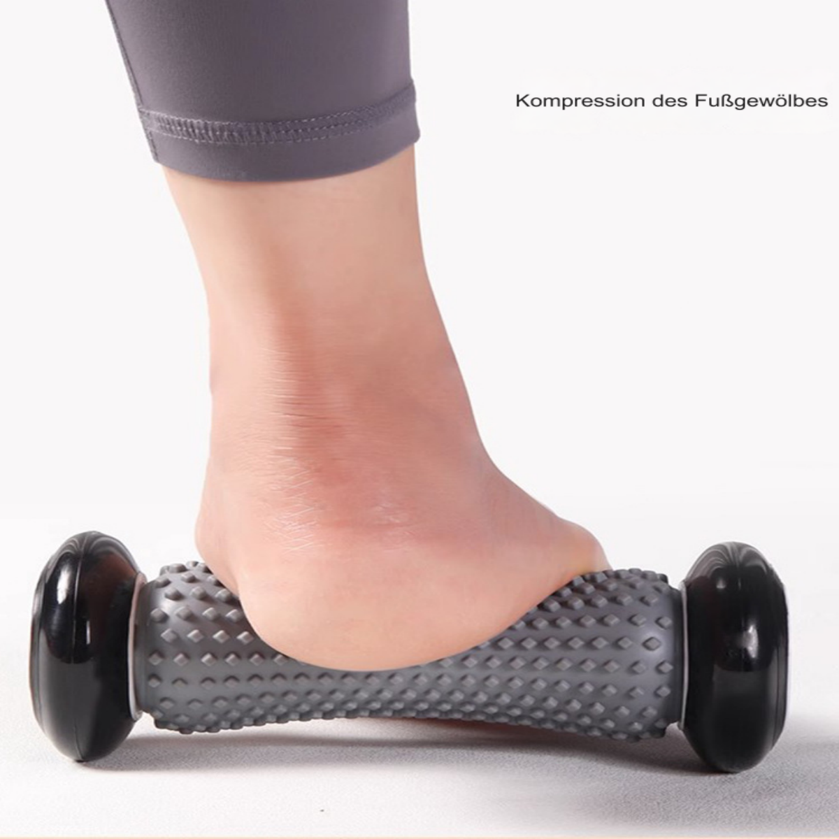 Fuß rollt auf grauem Fußroller. Bein in grauen Leggings.