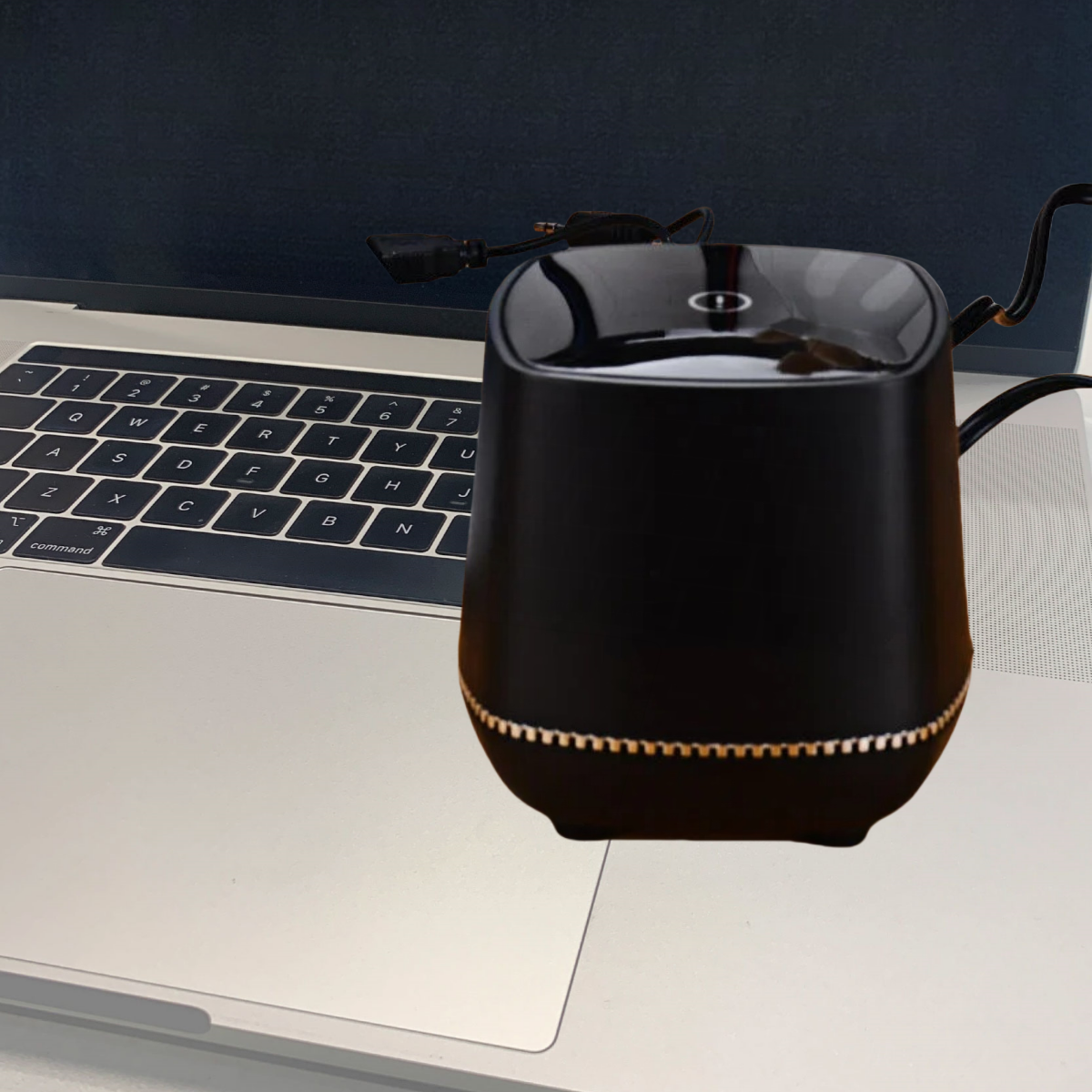 Schwarzer Lautsprecher auf einer Laptop-Tastatur. Ein schwarzes Netzkabel verbindet sich.