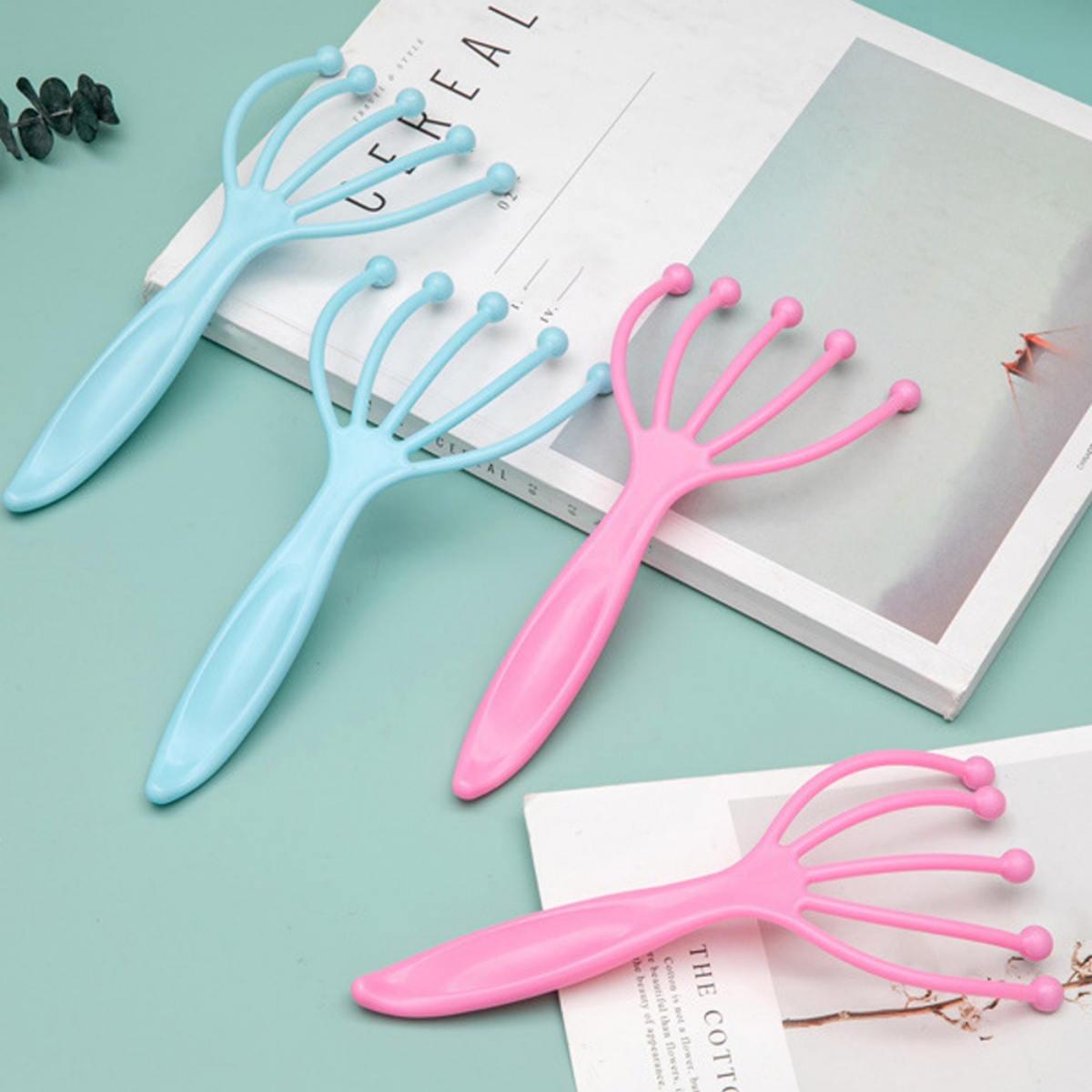 Vier Kopfmassagegeräte in Pink und Blau, auf einem Magazin.